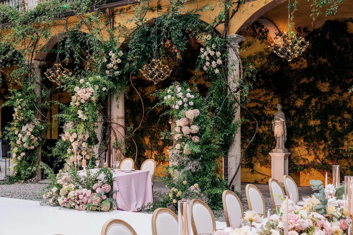 Wedding banquet table with floral centerpieces and place settings on a villa terrace by Lake Como